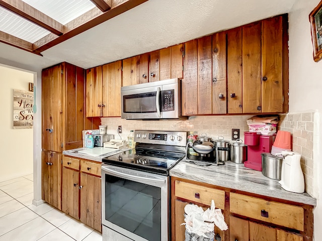 kitchen with stainless steel appliances, tasteful backsplash, and light tile patterned flooring