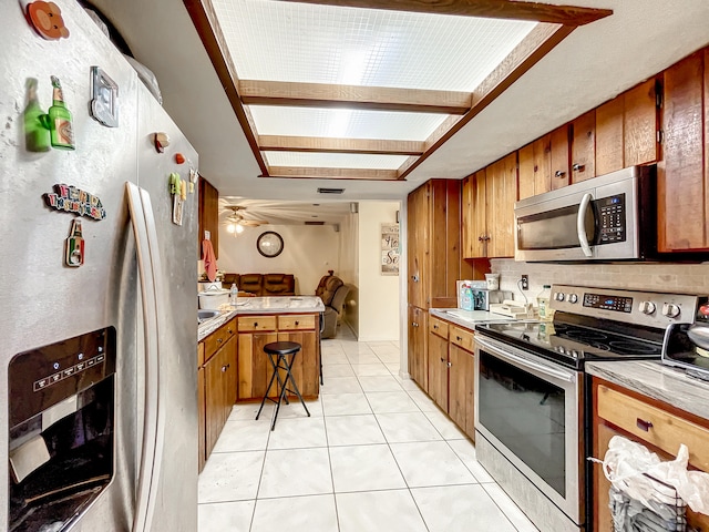 kitchen featuring decorative backsplash, light tile patterned flooring, stainless steel appliances, and ceiling fan