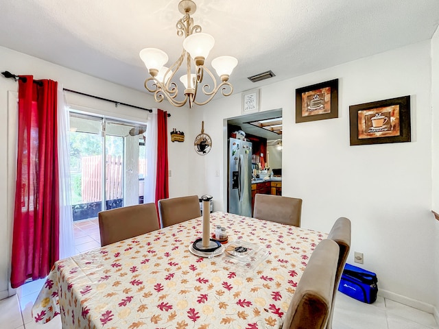 tiled dining room featuring a notable chandelier and a textured ceiling