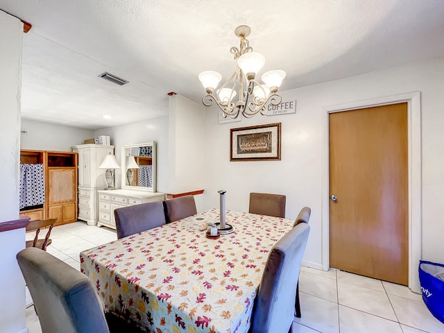 tiled dining area with a chandelier and a textured ceiling