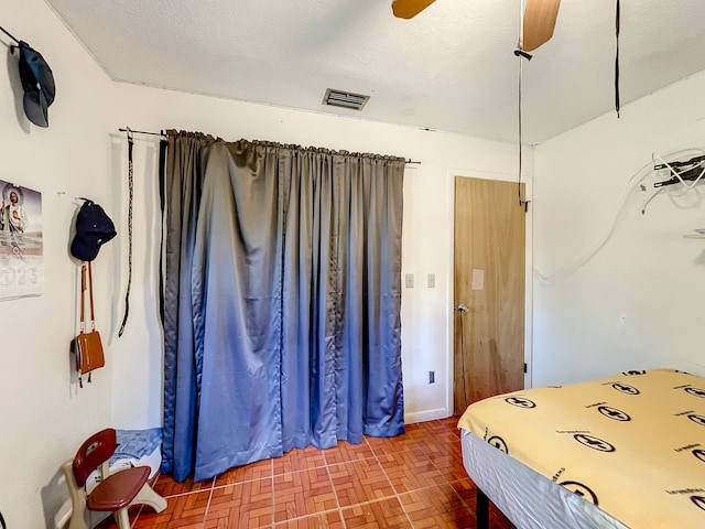 bedroom with ceiling fan and a textured ceiling