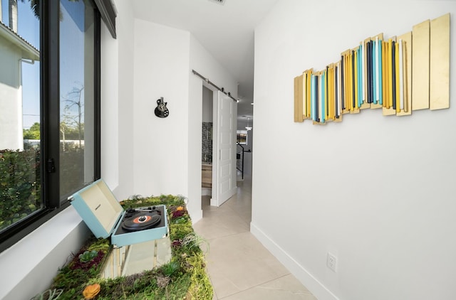 corridor featuring a barn door, plenty of natural light, and light tile patterned flooring