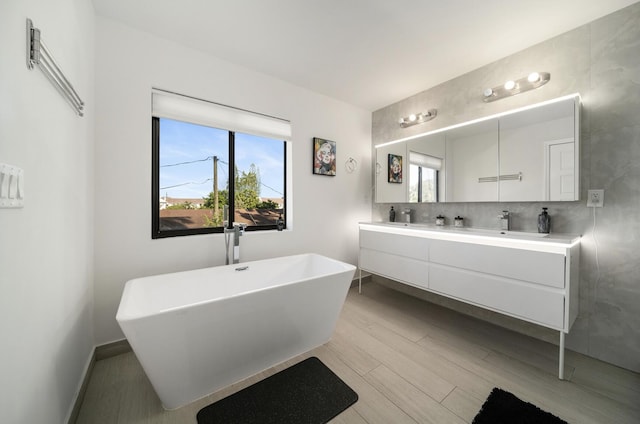 bathroom featuring vanity, wood-type flooring, a tub to relax in, and a wealth of natural light