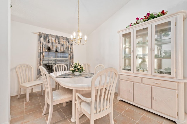 dining room with light tile patterned flooring, lofted ceiling, and an inviting chandelier