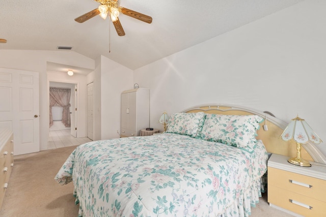 bedroom featuring ceiling fan, light colored carpet, a textured ceiling, and vaulted ceiling