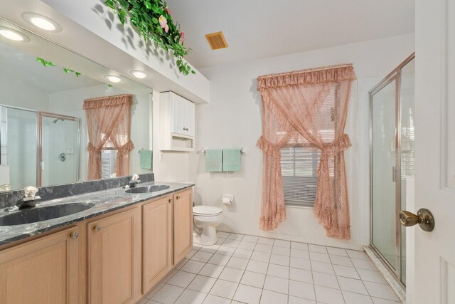 bathroom with tile patterned flooring, vanity, toilet, and walk in shower