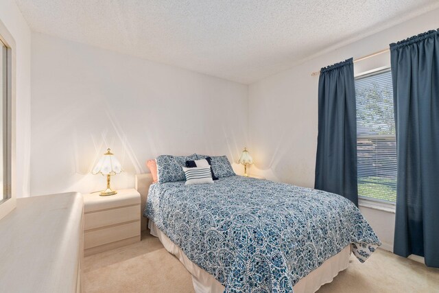 bedroom featuring a textured ceiling and light carpet