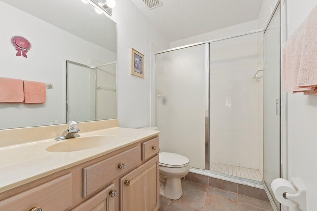 bathroom featuring tile patterned floors, vanity, an enclosed shower, and toilet