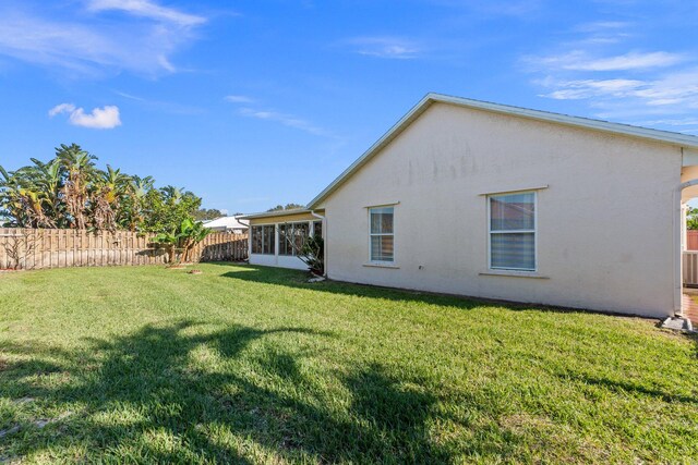 rear view of property featuring a sunroom and a lawn