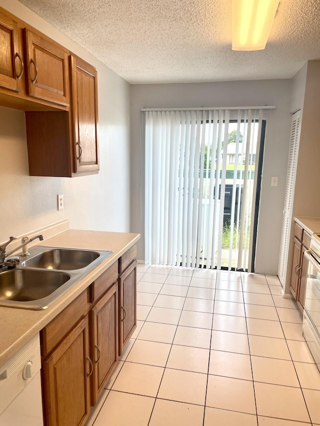 kitchen featuring a textured ceiling, sink, light tile patterned floors, and white appliances