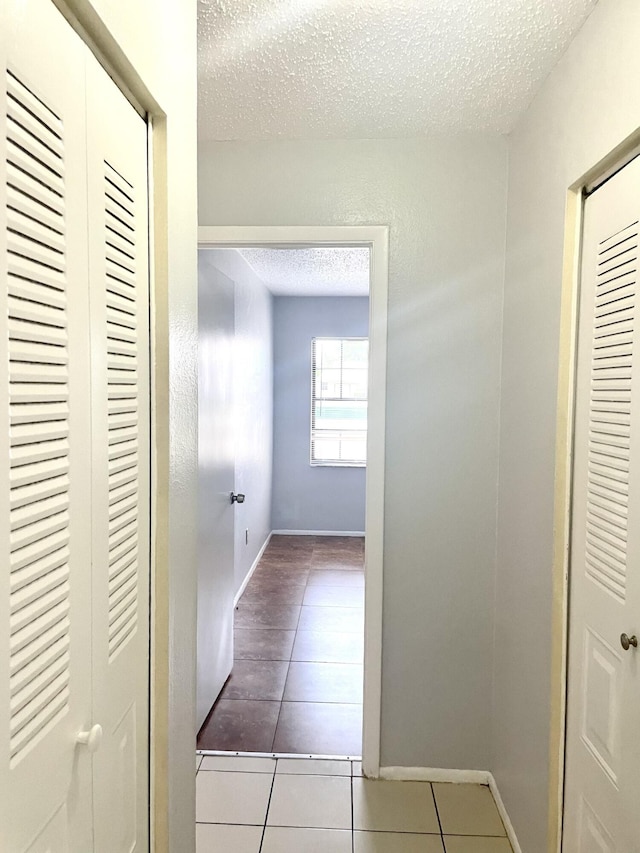 hall with tile patterned floors and a textured ceiling