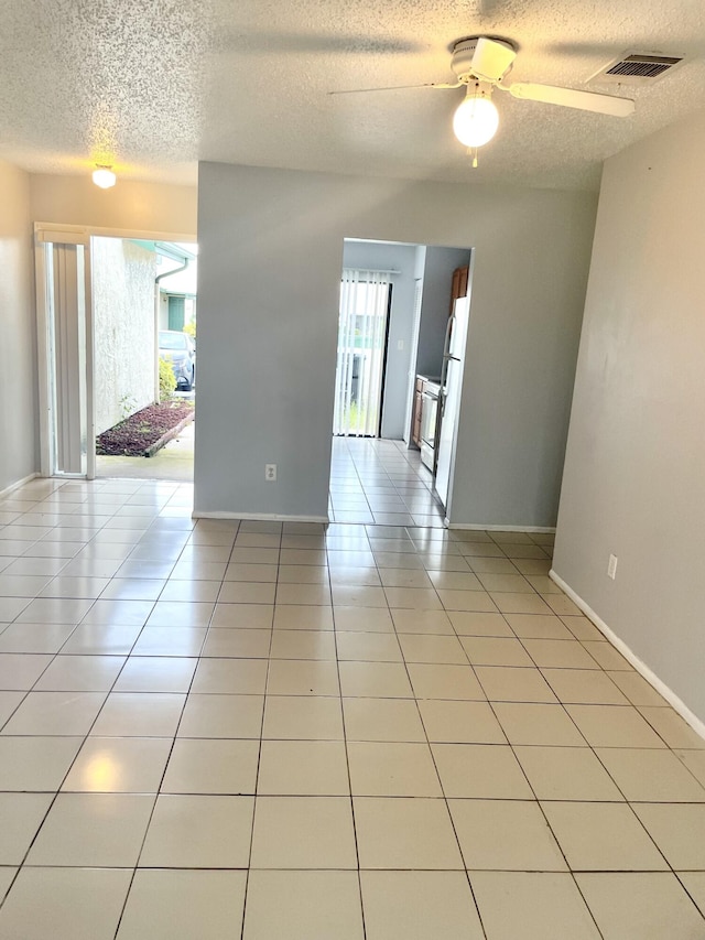 spare room with light tile patterned floors, a textured ceiling, and ceiling fan