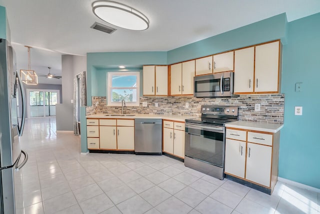 kitchen featuring appliances with stainless steel finishes, backsplash, ceiling fan, sink, and light tile patterned floors