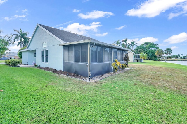 view of home's exterior featuring a sunroom, a yard, and a water view