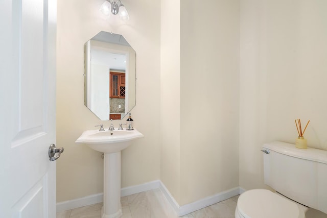 bathroom with toilet, sink, and tasteful backsplash