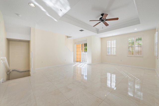 spare room featuring ceiling fan, a tray ceiling, crown molding, and a healthy amount of sunlight