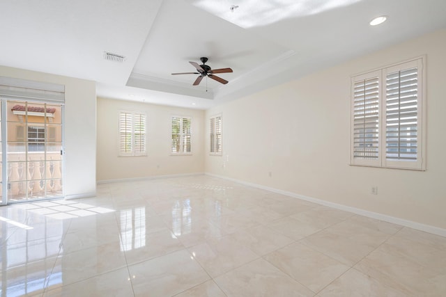 spare room featuring ceiling fan, a tray ceiling, and ornamental molding