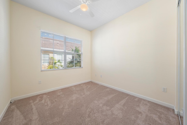 spare room with ceiling fan and light colored carpet