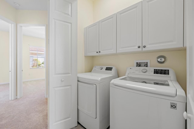 clothes washing area featuring washer and dryer, cabinets, and light carpet