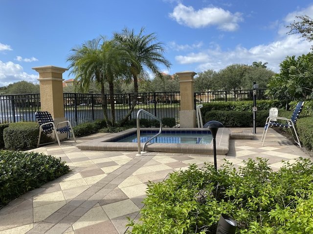 view of swimming pool featuring an in ground hot tub, a patio area, and a water view