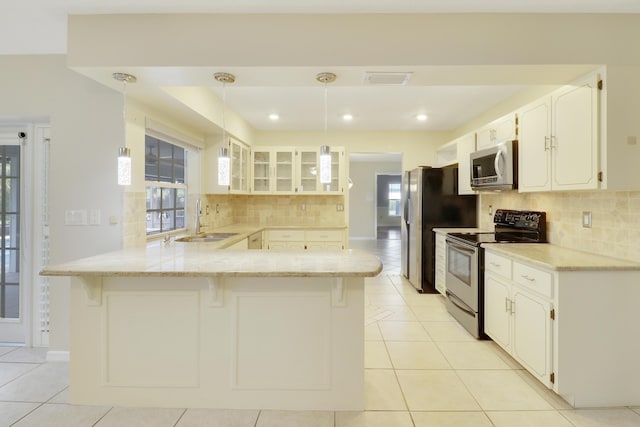 kitchen with pendant lighting, white cabinets, sink, appliances with stainless steel finishes, and kitchen peninsula