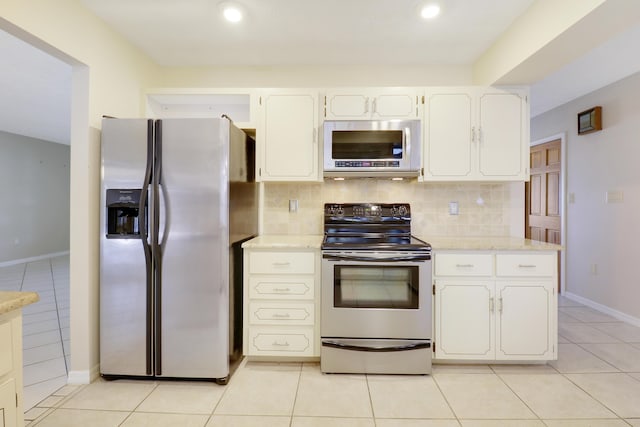 kitchen with tasteful backsplash, white cabinets, stainless steel appliances, and light tile patterned floors