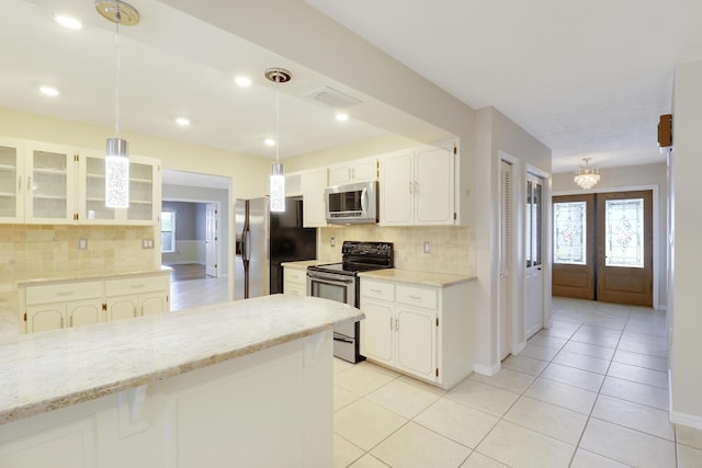 kitchen with pendant lighting, white cabinets, stainless steel appliances, and french doors