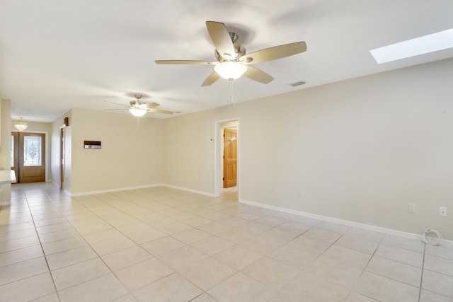 tiled spare room featuring a skylight and ceiling fan