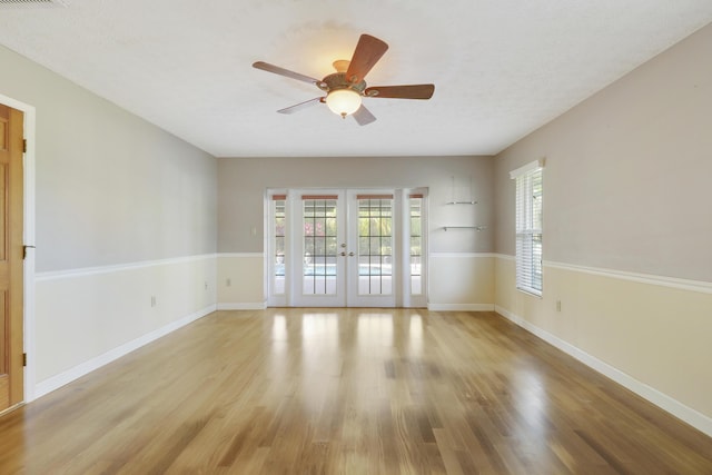 spare room featuring ceiling fan, light wood-type flooring, a textured ceiling, and french doors