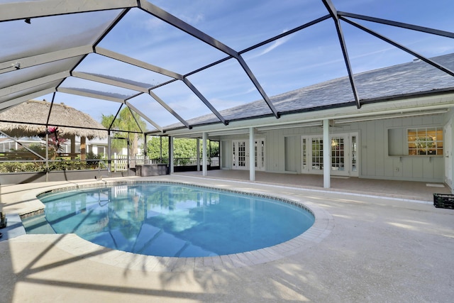 view of swimming pool with glass enclosure, ceiling fan, french doors, and a patio