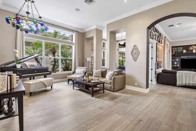 living room featuring a textured ceiling, light wood-type flooring, and ornamental molding