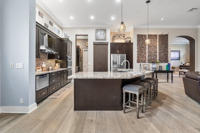 kitchen featuring pendant lighting, a spacious island, sink, dark brown cabinets, and stainless steel fridge with ice dispenser