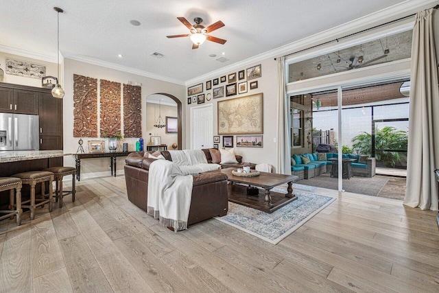 living room featuring ceiling fan, light hardwood / wood-style floors, crown molding, and a textured ceiling