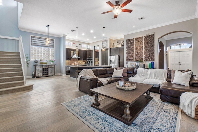 living room with ceiling fan, plenty of natural light, a textured ceiling, and light hardwood / wood-style flooring