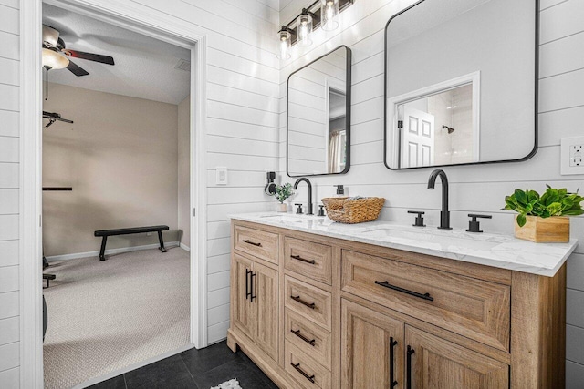 bathroom with tile patterned floors, ceiling fan, vanity, and wood walls