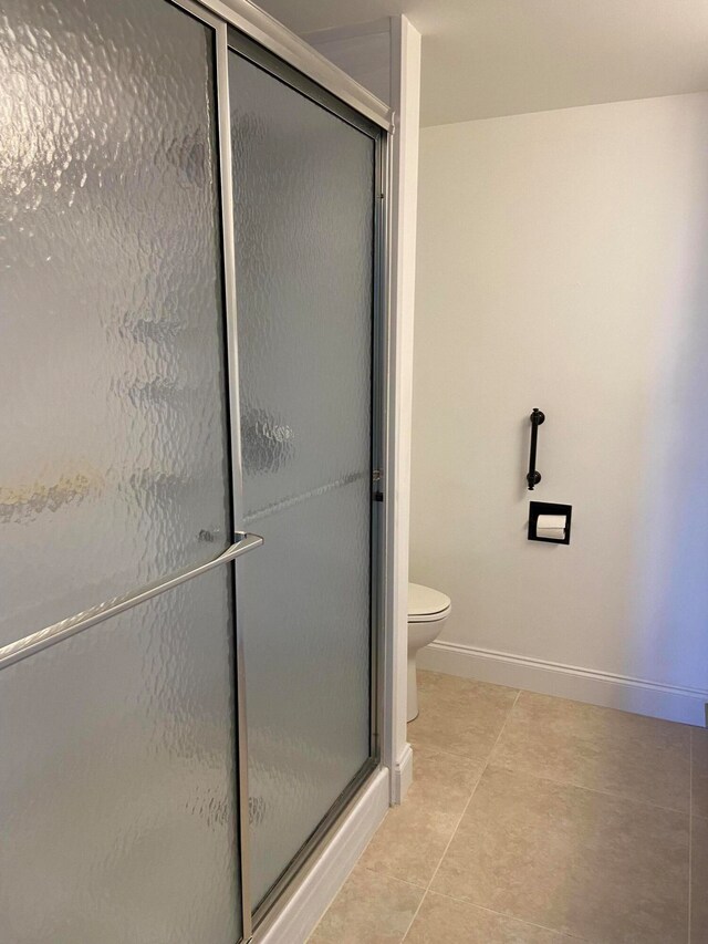 bathroom with tile patterned flooring, toilet, and walk in shower