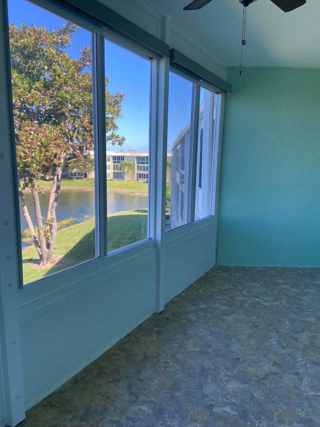 unfurnished sunroom with ceiling fan and a water view