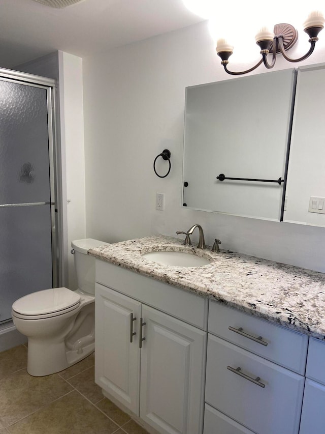 bathroom with toilet, vanity, tile patterned floors, and a shower with shower door