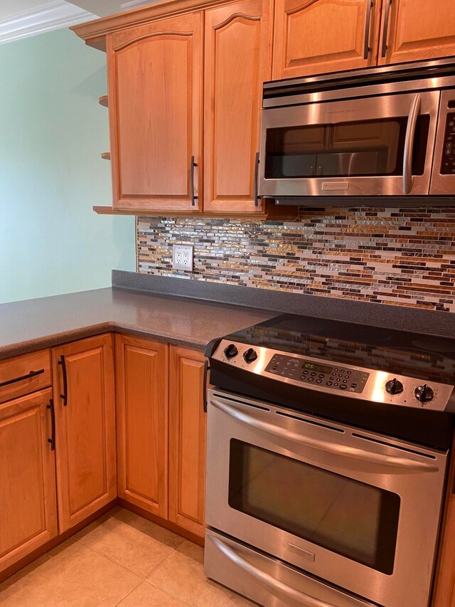 kitchen featuring decorative backsplash, crown molding, light tile patterned floors, and stainless steel appliances