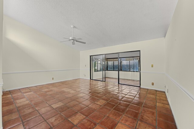 spare room featuring ceiling fan, vaulted ceiling, tile patterned floors, and a textured ceiling