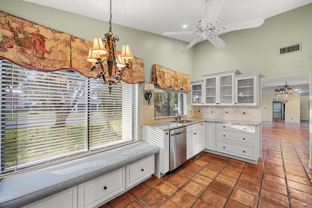 kitchen featuring white cabinetry, decorative backsplash, stainless steel dishwasher, hanging light fixtures, and ceiling fan with notable chandelier