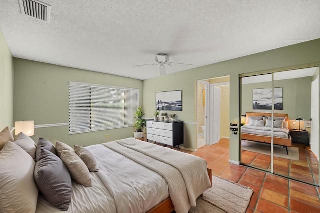 bedroom with a textured ceiling, ceiling fan, light tile patterned floors, and a closet