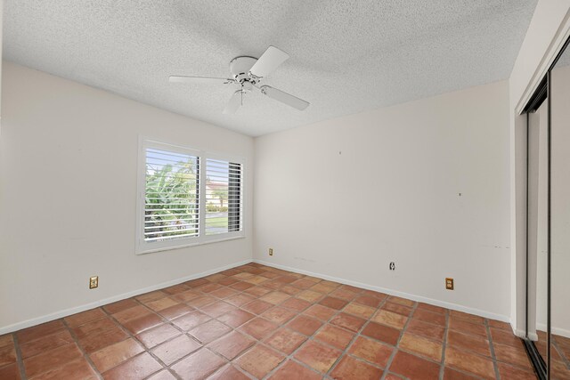 empty room featuring ceiling fan, a textured ceiling, and tile patterned floors