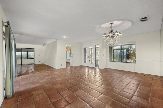 tiled spare room featuring french doors, a textured ceiling, and a notable chandelier