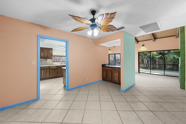 kitchen featuring beamed ceiling, backsplash, ceiling fan, and light tile patterned flooring