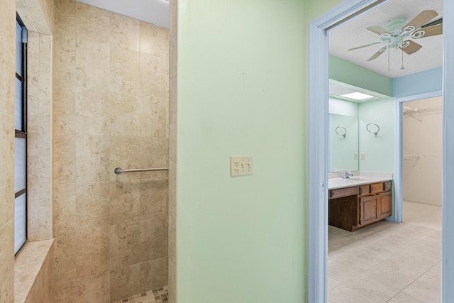 bathroom featuring a textured ceiling, vanity, ceiling fan, and tiled shower