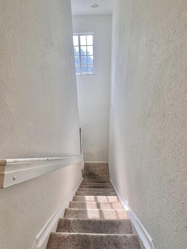 stairway with baseboards and a textured wall