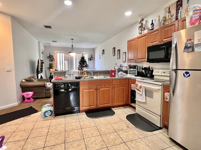 kitchen featuring a peninsula, light tile patterned floors, black appliances, and a sink