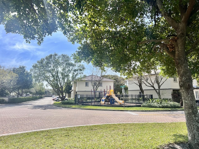 exterior space featuring playground community, stucco siding, fence, and a front yard