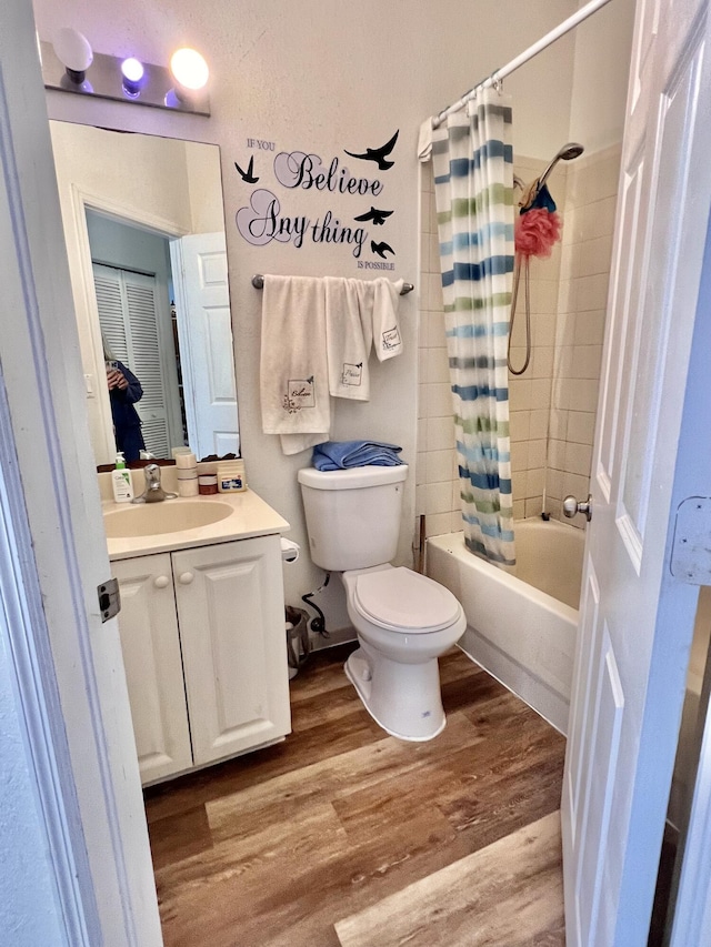 bathroom featuring toilet, vanity, shower / bath combo with shower curtain, and wood finished floors
